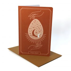 Artistic Easter greeting card featuring hands encircling a star-filled egg with an envelope underneath it
